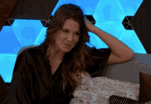 a woman is sitting on a couch with her hand on her head