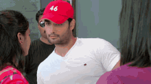 a man wearing a white shirt and a red hat with the number 46 on it