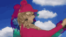 a woman in a pink hat is standing in front of a blue sky and clouds