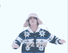 a person wearing a hat and a sweater with snowflakes is standing in the snow