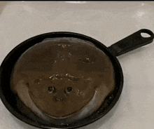 a frying pan filled with a brown liquid that looks like a dog 's face