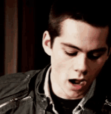 a close up of a man wearing a leather jacket with his mouth open