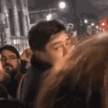 a man is talking on a cell phone while standing in a crowd .