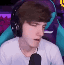 a young man wearing headphones and a white shirt is sitting in a chair .