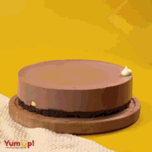 a chocolate cake sits on a wooden cutting board with the words yumup written on the bottom
