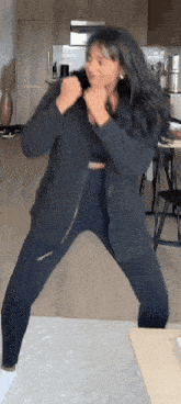 a woman is dancing in a living room while wearing a black jacket .