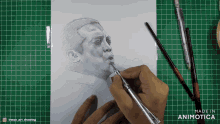 a person is drawing a man with a pen on a cutting board that says made in animatica