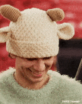 a man wearing a knitted hat with ears and a green sweater