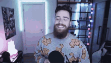 a man with a beard is wearing a garfield sweater and singing into a microphone .
