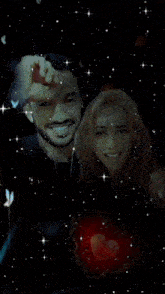 a man and a woman are posing for a picture in front of a red heart