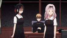 a man sits at a desk with two girls standing behind him