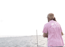 a man in a pink shirt stands on a boat