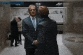 a man in a suit and tie talks to another man in a hallway with the name tmeclownland2 visible