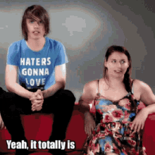 a man in a haters gonna love shirt sits next to a woman in a dress