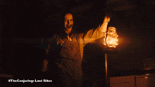 a man in overalls is holding a lantern in a dark room