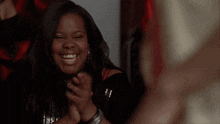 a woman in a black top is smiling and holding her hands up