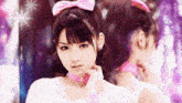 a girl with a pink bow in her hair is looking at herself in the mirror