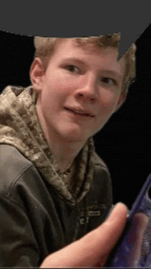 a young man is holding a cell phone in his hand and smiling .