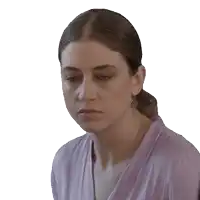 a woman wearing a purple shirt and earrings looks down at something