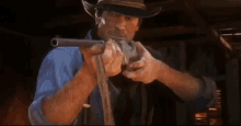 a man in a cowboy hat is holding a gun in his hand and pointing it at the camera .