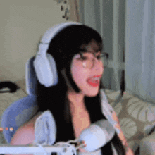a woman wearing headphones and glasses is sitting in front of a microphone in a room .