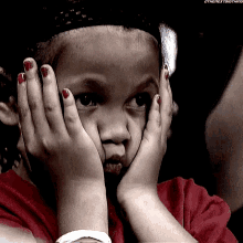 a little girl with red nail polish on her nails is covering her face with her hands