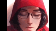 a close up of a person wearing glasses and a red hood .