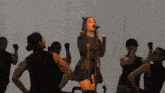 a woman singing into a microphone surrounded by a group of dancers