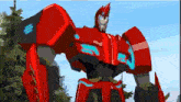 a red robot from the transformers animated series is standing in a forest .