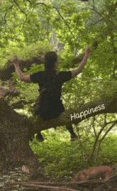 a person sitting on a tree branch with the word happiness written on it