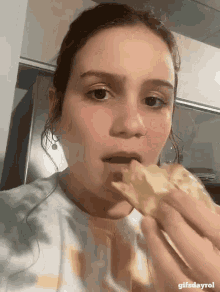 a close up of a woman eating a slice of pizza with gifsdayrol in the bottom right corner
