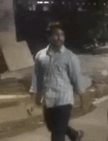 a man in a white shirt and black pants is standing on his knees in a dark room .