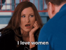a woman says i love women in front of a man in a blue shirt