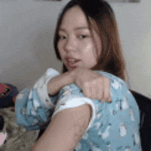 a woman in a blue pajama top is holding her arm over her shoulder .