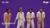 a group of men singing into microphones with a dingo logo in the background