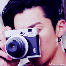 a close up of a person holding a camera with the words bluemallowz on the bottom right