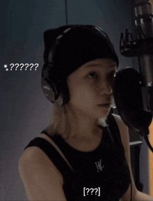 a woman wearing headphones and a black tank top with the letter w on it is talking into a microphone