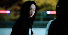 a woman wearing a black hoodie looks at the camera