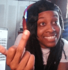 a woman wearing headphones and a baseball cap giving the middle finger
