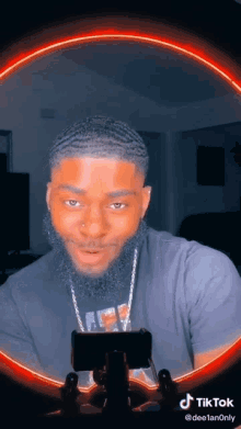 a man with a beard is taking a picture of himself with a red light behind him .