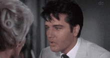 a man in a suit and tie is talking to a woman with the letters dc above him