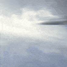 a plane is flying through a cloudy sky with a few white clouds