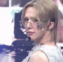 a woman wearing glasses and a microphone is looking at the camera