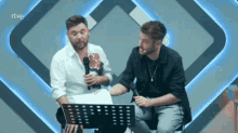two men are sitting in front of a microphone with rtve written on the bottom of the screen