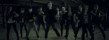 a group of young people are dancing in a dark room .