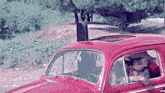 a man driving a red car with a sunroof