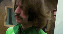 a man in a green shirt with a mustache