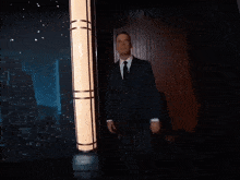 a man in a suit and tie is waving his hand in a dark room