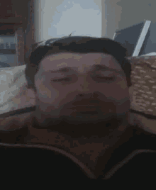 a man with a beard is sitting on a couch and making a funny face