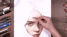 a person is drawing a woman 's face with pencils on a table